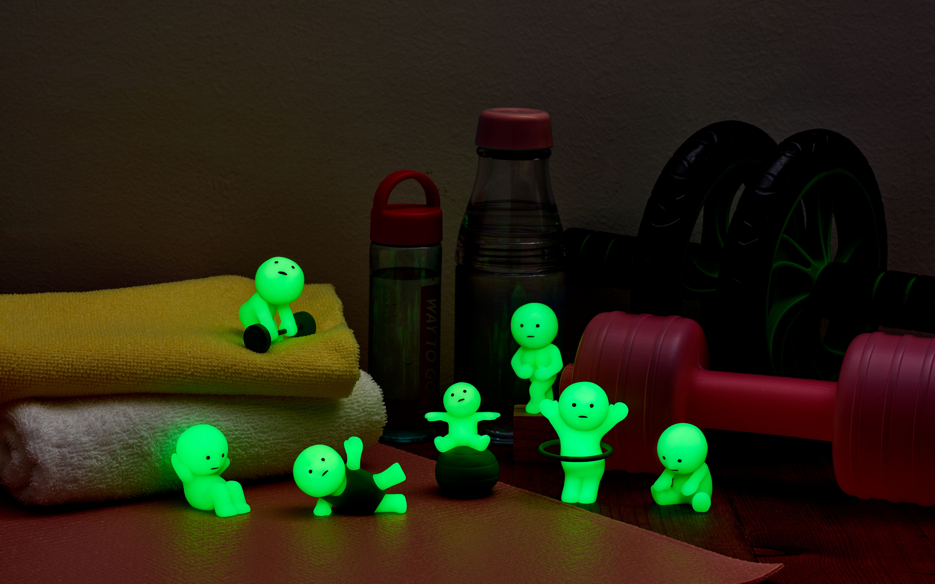 smiski exercising full series on a wooden backdrop with various gym-themed props. background is dark and all figures are glowing bright green