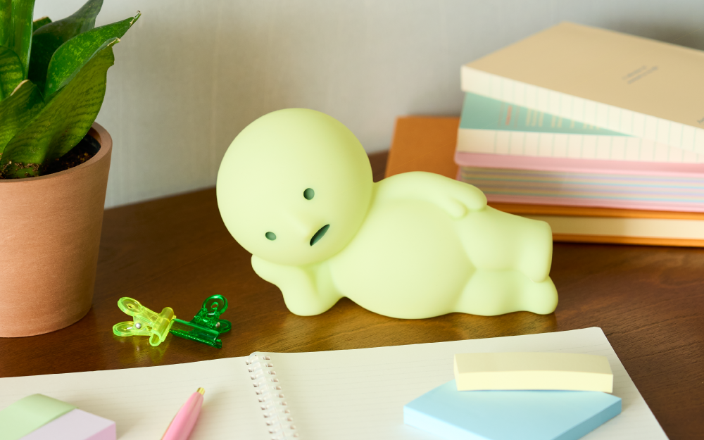 SMISKI Touch Light, Lounging, on a wooden surface with a books, notepads, clips and a potted plant around it.