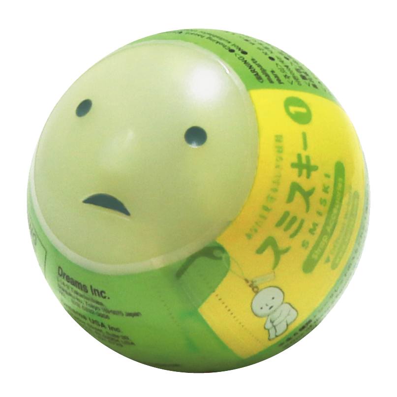 transparent background image of the smiski strap accessory gachapon capsule in its shrink plastic packaging. gachapon capsule is shaped like a smiski head